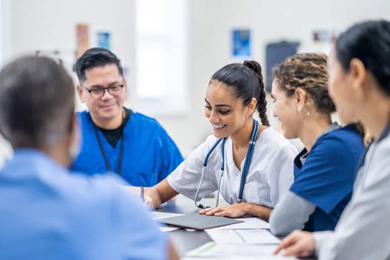 Prise de notes lors d'une réunion médicale avec une équipe de professionnels de santé.